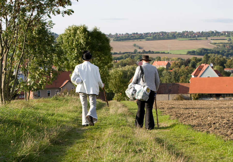 Zwei Bäcker auf der Walz gehen über eine Wiese