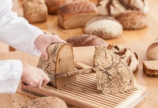 Prüfer schneidet Brot