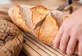 Bäcker schneidet ein Brot