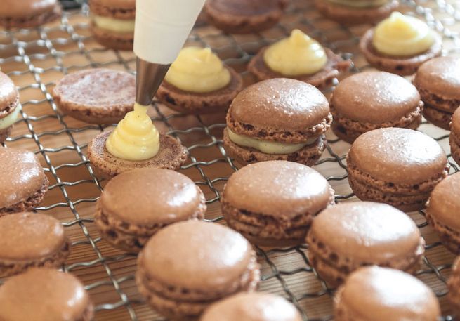 Creme wird auf Macarons platziert