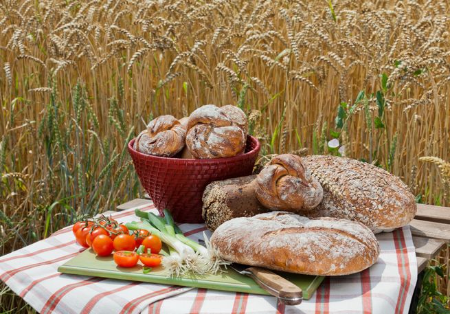 brote broetchenkorb und frisches gemüse im kornfeld